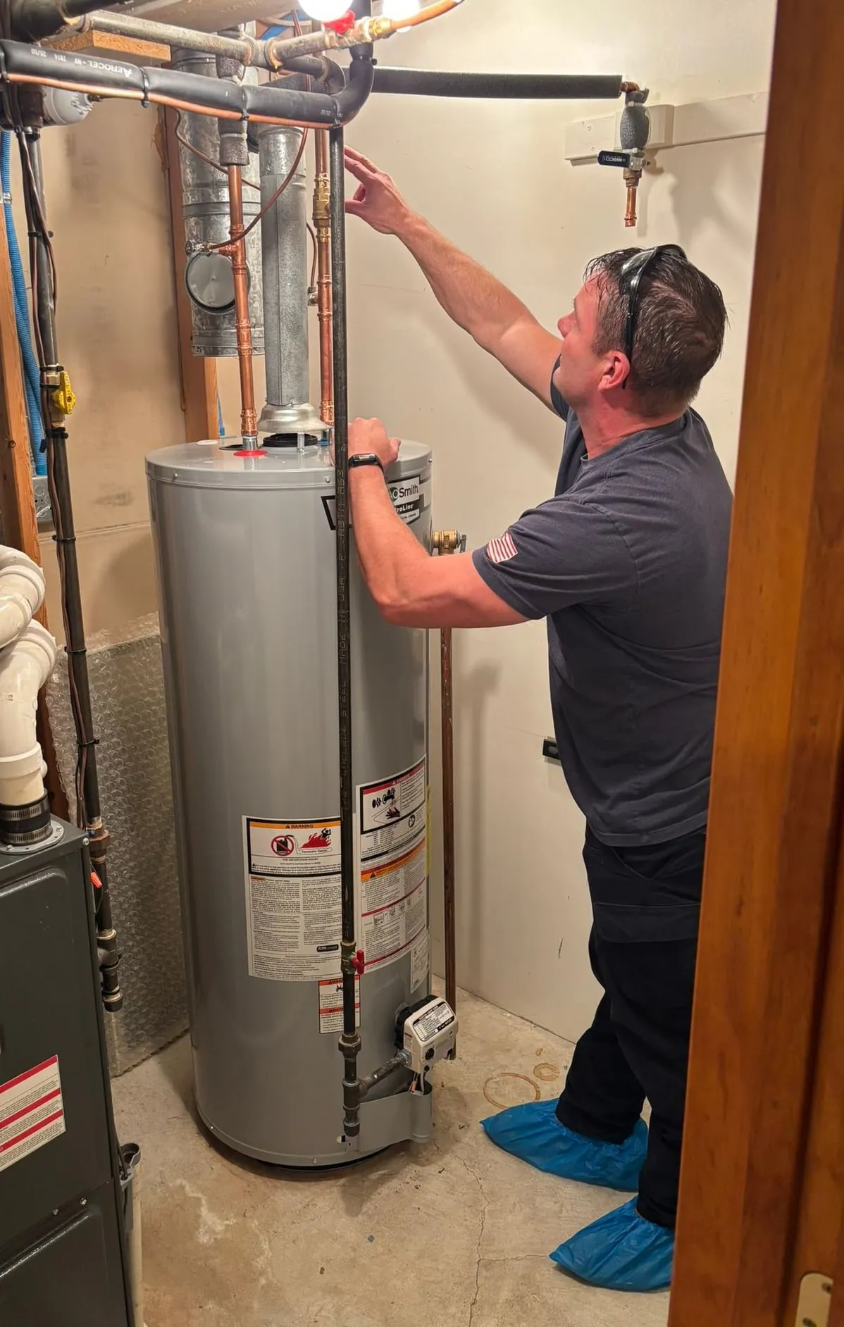 Mike Livingston, Christopherson Mechanical technician, working on copper supply lines above an A.O. Smith water heater in a finished basement.